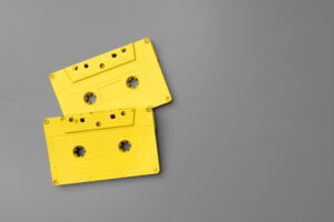 Yellow audio cassettes on gray background top view